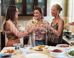 Im glad you girls are part of my life. Cropped shot of a group of cheerful young friends having a celebratory toast with drinks while standing in the kitchen preparing food at home.