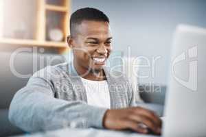 Connect to the world from the comfort of home. Shot of a happy young man using a laptop while relaxing at home.