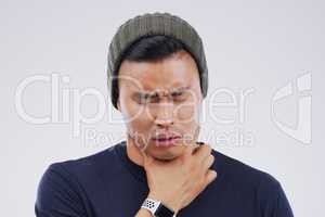 It feels like something is chocking me. Studio shot of a young man suffering with a sore throat against a grey background.