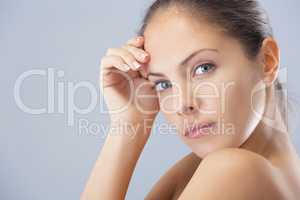 Shes simply stunning. Head and shoulders studio shot of a beautiful young woman against a blue background.