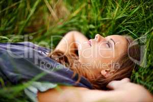 Relaxing in natures nest. Portrait of a beautiful woman lying in the grass.