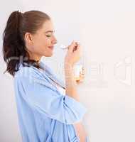 Yummy yoghurt for mom and baby. Shot of a pregnant woman enjoying a snack at home.