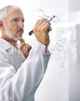 Hes involved in cutting edge research. Shot of a mature male scientist drawing a molecular structure on a glass surface.