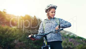 Checking her time. Shot of a female mountain biker out for an early morning ride.