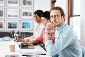 So many plans to try out. Cropped portrait of a handsome young businessman sitting and looking contemplative while his colleagues work behind him in the office.