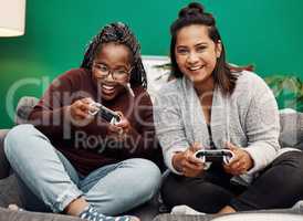 Girls night in for the gaming fanatics. Shot of two young women playing video games on the sofa at home.