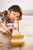 Hes a skilled carpenter. A handsome young carpenter measuring and marking wood.