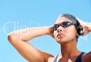Cultivating a winners mindset. Determined young female swimmer adjusting her swimming goggles.