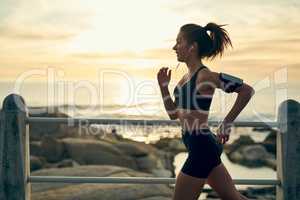 Wake up and run. Shot of a sporty young woman running along the esplanade.