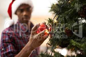 Christmas is my favourite time of year. Shot of a handsome young man decorating a christmas tree.