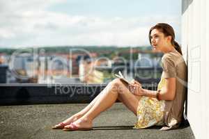 Seeking inspiration - Writers. Young woman journaling while seated on a rooftop.