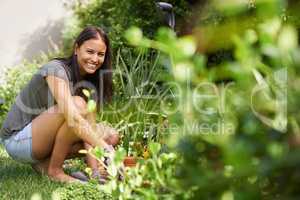 Keeping my plant beds moist and nourished. Full length shot of a pretty brunette working in her garden.