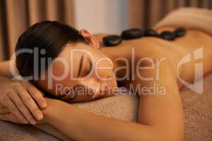 Soothing stones. A young woman enjoying hot stone therapy at the spa.