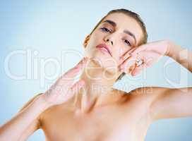 Perfectly effortless beauty. Studio portrait of a beautiful young woman feeling her skin against a blue background.