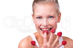 Berry delicious. Shot of a beautiful young woman playfully eating raspberries off her fingertips.