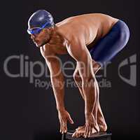 Train insane or remain the same. Studio shot of a handsome swimmer ready to dive off the starting block.