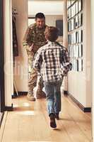 Guess whos home. Rearview shot of a little boy running to greet his father as he returns from the army.