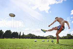 What a beautiful kick. Wide action shot of a young man kicking a rugby ball.