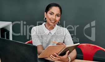 Its vital to plan as far as you can. Portrait of a young businesswoman writing in a notebook while working in an office.