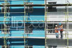 Watch the experts in action. Shot of a young man and woman going over building plans at a construction site.