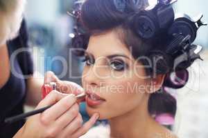 Every girl loves to be pampered. A young model at the hair salon having lipstick applied.