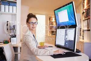 My dual-screen gives me increased productivity. Portrait of a young woman working on a dual-screen computer at home.