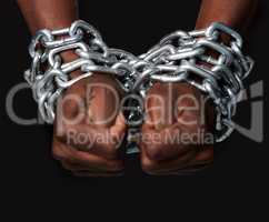 Slave to the system. Cropped shot of a mans hands tied up with chains against a black background.