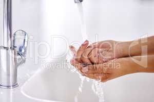 Practicing healthy hygiene habits. Cropped shot of a woman washing her hands at a sink.