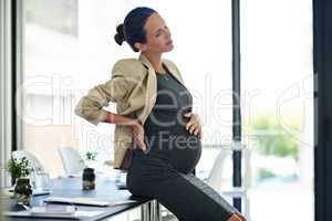 Third trimester aches. Shot of a pregnant businesswoman in discomfort in her office.