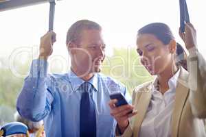 Bonding on the bus. Two young colleagues traveling on the bus and holding onto the hand straps.