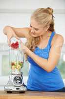 Getting ready to blend the perfect smoothie. Attractive young woman making a fruit smoothie.