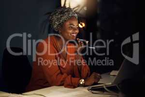 Its faster than typing. Shot of a young businesswoman talking on a cellphone while using a laptop in an office at night.