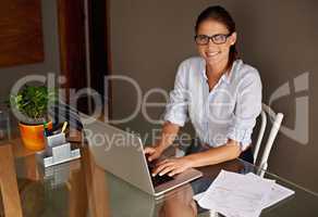 My home and my office - The best of both worlds. An attractive young woman working from her home office.