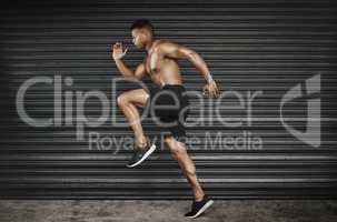 Feeling good and keeping fit. Shot of a fit and shirtless young man running.