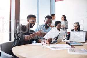 Look at how our profits have skyrocketed. Shot of two businessmen going through paperwork together in an office with their colleagues in the background.