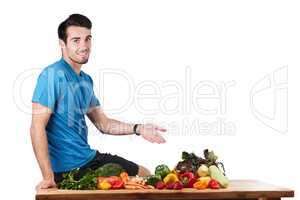 Fresh veg is on the menu today. Studio portrait of a handsome young man posing with a variety of fresh vegetables against a white background.