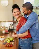 Making healthy choices as a couple. Shot of a young man hugging his wife while she prepares a healthy snack at home.