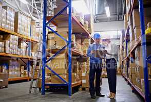 We know where every order is in this warehouse. Shot of a man and woman inspecting inventory in a large distribution warehouse.