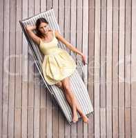 Relaxing in style. A young, wealthy woman lying on her sunbed in a summer dress.