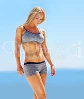 Whole body fitness. Shot of a beautiful blond woman in sportswear standing outside with the ocean in the background.