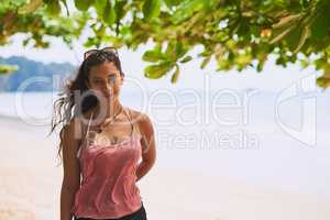 Shes a sucker for summer. Portrait of a happy young tourist posing in front of an ocean view.