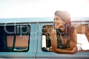 Off to see whats out there. Shot of a happy young woman leaning out of the window during a road trip.