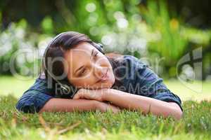 Dreaming of things to come. Shot of an attractive young woman lying on the grass and listening to music.
