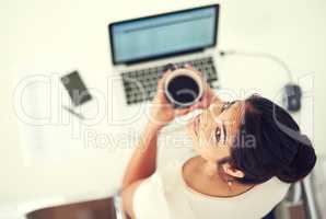 Im setting my sights on the top. High angle portrait of a young businesswoman drinking coffee while working at home.