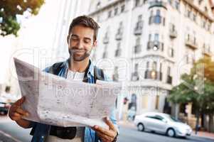 Im exactly where I want to be. Cropped shot of a handsome young man looking at a map while touring a foreign city.