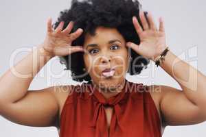 Sprinkle some silliness on it. Studio shot of a young woman making a funny face against a gray background.