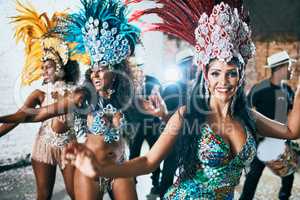 We are here to entertain you. Cropped shot of beautiful samba dancers performing in a carnival with their band.