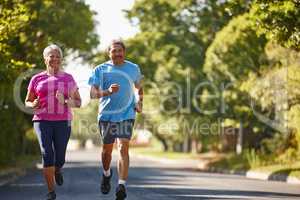 Happiness and healthiness is our goal. Shot of a mature couple jogging together on a sunny day.
