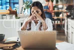 Im praying for a miracle to happen. Shot of a woman looking stressed while working from a cafe.