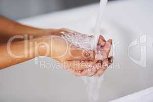 Preventing the spread of germs. Cropped shot of a woman washing her hands at a sink.